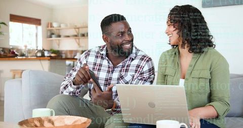 Couple collaborating on laptop and tablet in bright open-plan living room, sharing ideas