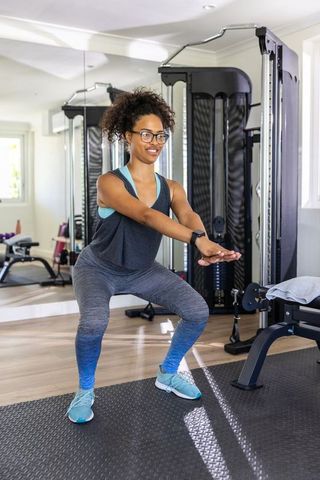 Confident woman performing squat exercise at home gym
