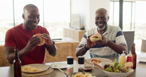 Father and Son Smiling While Eating Burgers and Fries Together - Download Free Stock Images Pikwizard.com