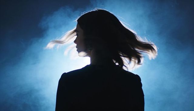 Backlit silhouette woman turning hair in fog with rimlight, cinematic moody atmosphere
