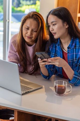 Mother and Daughter Sharing Technology at Home Kitchen Table