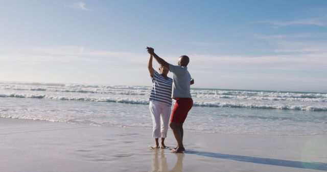 Senior african american couple dancing at the beach. healthy outdoor leisure time by the sea.