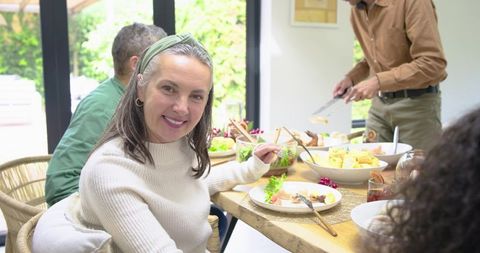Multigenerational Family Dining Together at Wooden Table, Mature Woman Smiling Warmly