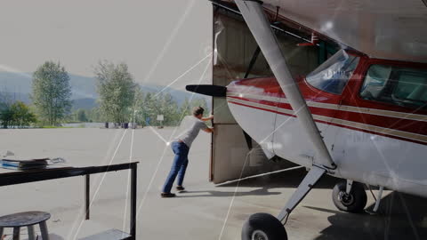 Man Preparing Private Plane in Hangar Against Nature Backdrop