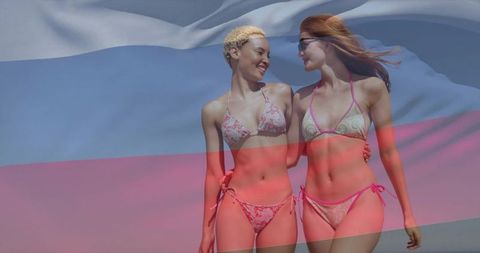 Two Women in Bikinis Walking on Beach with Flag Overlay