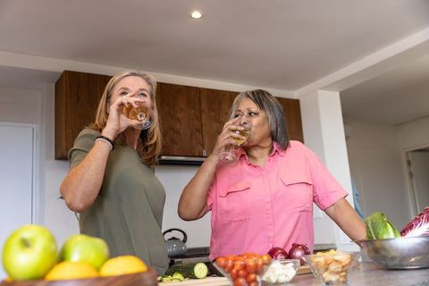 Senior Female Friends Enjoying Wine While Preparing Meal