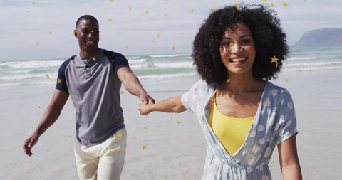 Couple walking hand-in-hand on sunny beach with golden star confetti, coastal romance
