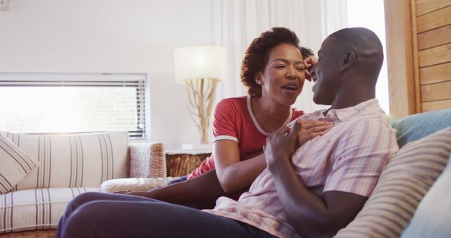 Image of happy african american couple sitting on sofa and talking. Love, relationship and spending quality time together concept.