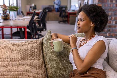 Professional african american woman enjoying coffee break in modern office lounge