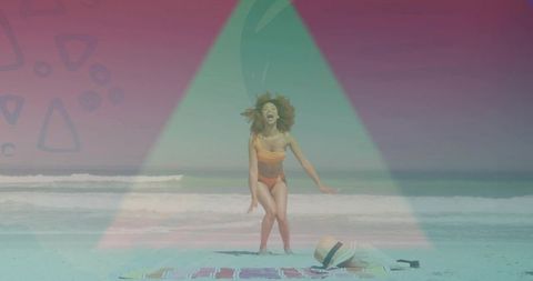 Joyful woman jumping on sunny beach in orange bikini with neon triangle overlay and sunhat