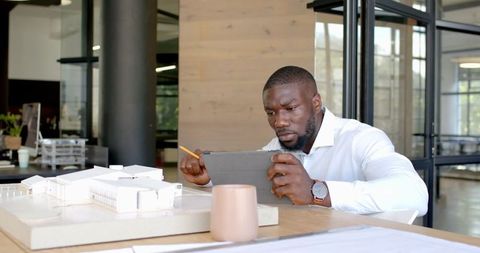 Architect using tablet for building model review in modern office
