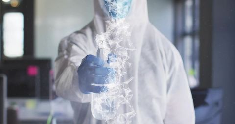 Technician wearing protective suit and spraying disinfectant with glowing particle network