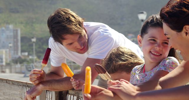 Perfect for depicting summer fun, this image features a family enjoying ice pops outdoors. Ideal for use in advertisements focusing on family products, travel destinations, or summer activities. It suggests warmth, happiness, and togetherness, making it suitable for promotional material aimed at families or wellness-related content.