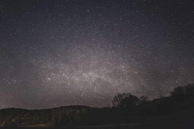 This is a beautiful and serene night sky filled with stars and constellations seen over a forest backdrop. Ideal for use in projects related to astronomy, nature, nighttime, and outdoor adventures. Perfect for backgrounds, web design, educational materials, and promotional content that highlights the beauty of the cosmos and natural landscapes.