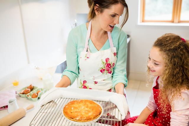 Mother interacting with daughter while holding pancake in cooling rack - Download Free Stock Photos Pikwizard.com