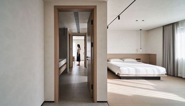 Standing woman watching sunlight in minimalist modern bedroom and tiled corridor