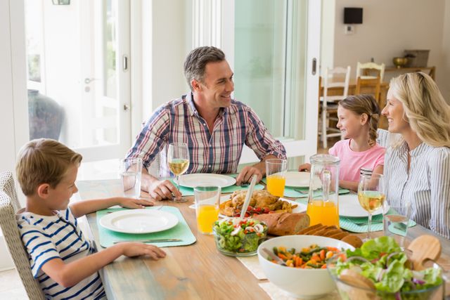 Family sitting around dining table, sharing a meal and enjoying each other's company. Perfect for illustrating family bonding, home lifestyle, healthy eating, and togetherness. Suitable for use in advertisements, family-oriented articles, and lifestyle blogs.