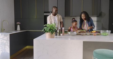 African American family cooking on marble island chopping vegetables and making salad