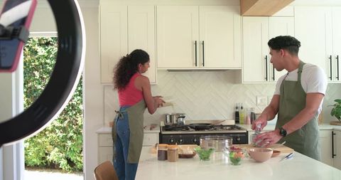 African american couple cooking together in bright modern kitchen with island and stove