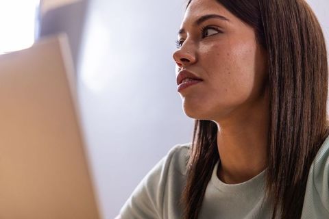Young woman looking thoughtfully while working on laptop close-up portrait for remote work