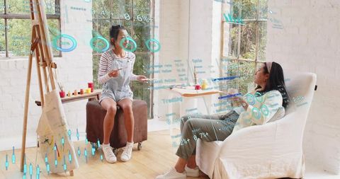 Sunlit art studio collaboration with women painting and augmented reality data overlays