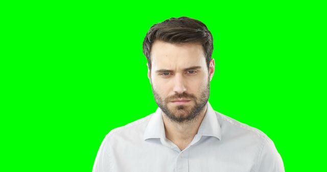 Man with a serious expression looking directly at camera against green screen background. Perfect for cropping and editing in diverse contexts. Suitable for business presentations, advertising, social media posts, and digital content creation.