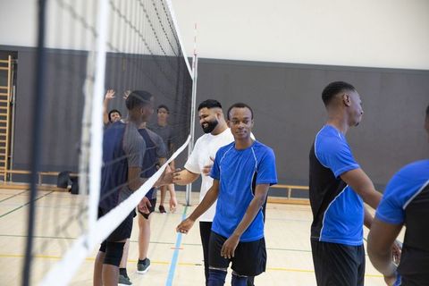African american teens shaking hands after indoor volleyball match showing sportsmanship