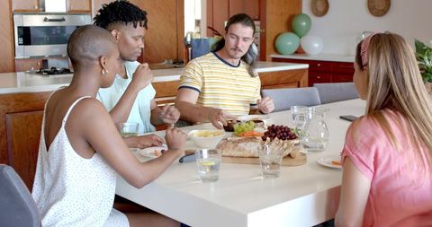 Diverse Group of Friends Enjoying Lively Kitchen Snack Moment