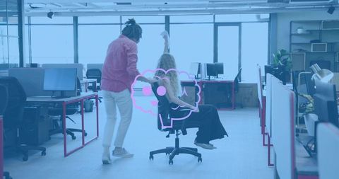 Pushing coworker in rolling chair through bright open-plan office, playful team momentum
