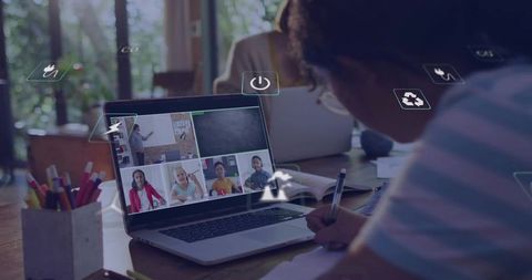 Writing student taking notes during remote class on laptop with virtual classroom grid daylight