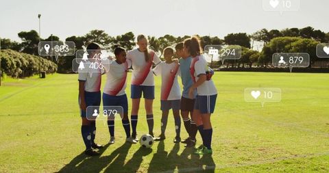 Girls soccer team huddling on sunlit pitch with social media icons representing engagement