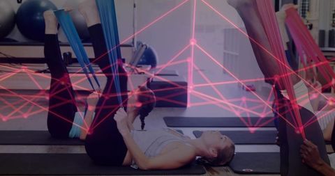 Performing supine leg raises with resistance bands in group fitness class
