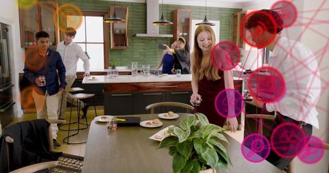Friends taking selfie in modern kitchen, mingling around table with drinks and snacks