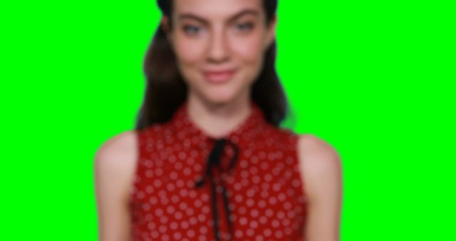 Portrait of a woman wearing a red polka dot top with green screen background. Excellent for use in various visual media projects such as advertisements, websites, or social media posts where you may want to add a custom background or effect.