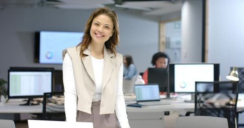 African american businesswoman leaning on desk smiling in modern open-plan office, team leader