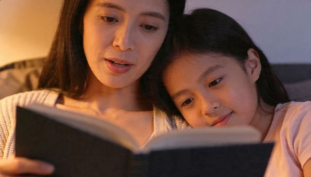 Mother and daughter reading bedtime story on couch, cozy evening family bonding moment