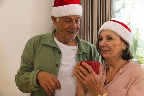 Senior couple celebrating christmas with festive hats and warm drink