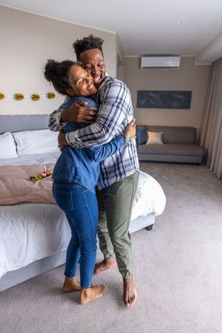 Couple embracing in cozy modern master bedroom celebrating romantic intimate moment