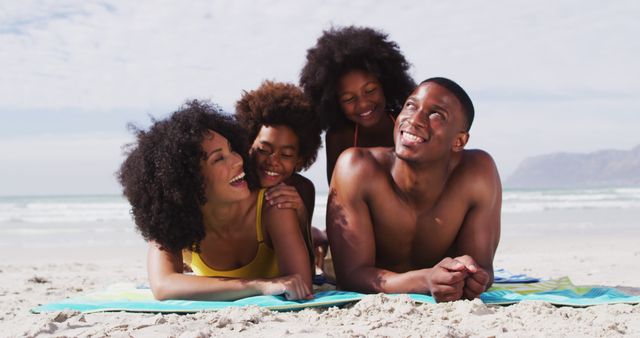 Portrait of african american parents and two children lying on a towel at the beach smiling - Download Free Stock Photos Pikwizard.com