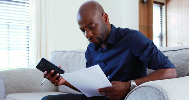 Man Reviewing Documents on Couch in Modern Living Room - Download Free Stock Images Pikwizard.com