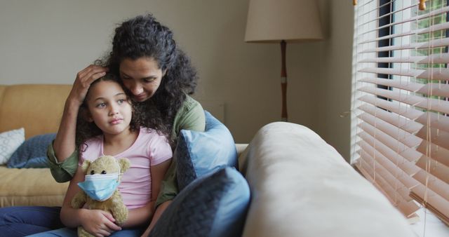 Biracial mother and daughter hugging,daughter holding tedy bear with face mask - Download Free Stock Photos Pikwizard.com
