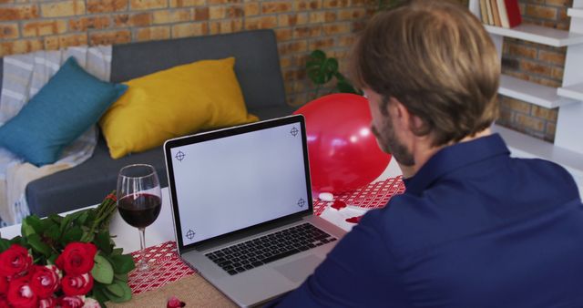 Man is preparing a romantic video call date. Image can be used for romantic occasion promotions, online dating services or Valentine's Day campaigns.