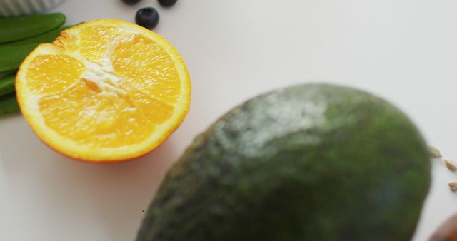 Close-Up of Fresh Avocado and Half Orange on White Surface - Download Free Stock Images Pikwizard.com