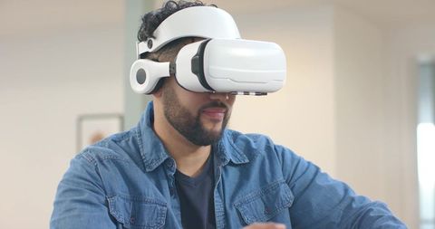 Mid-adult man exploring virtual world with white VR headset in modern home office