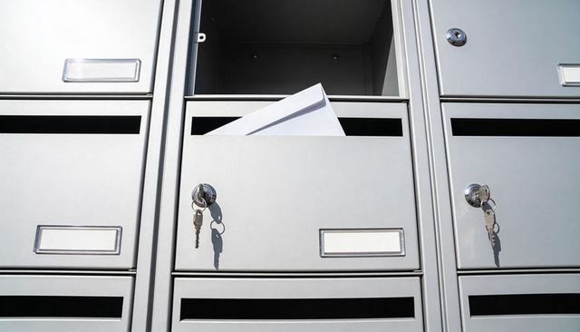 Minimalist mailbox holding white envelope and keys in chrome lock close-up for security