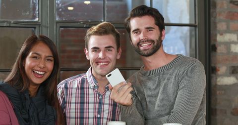 Diverse Group of Young Adults Smiling at Casual Cafe Gathering