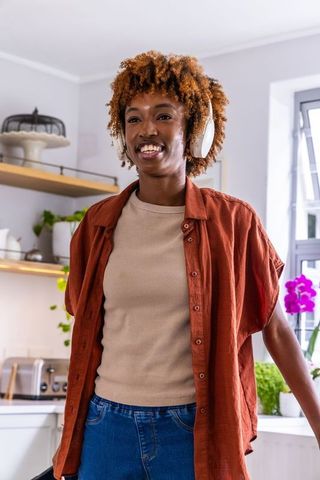 African american woman listening to music on wireless headphones in bright modern kitchen