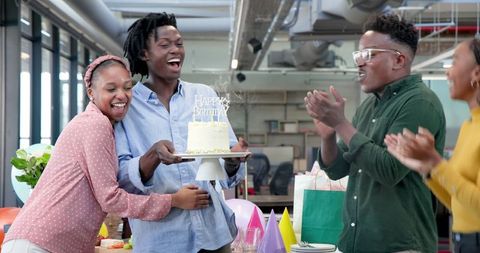 Office birthday celebration with happy colleagues and cake