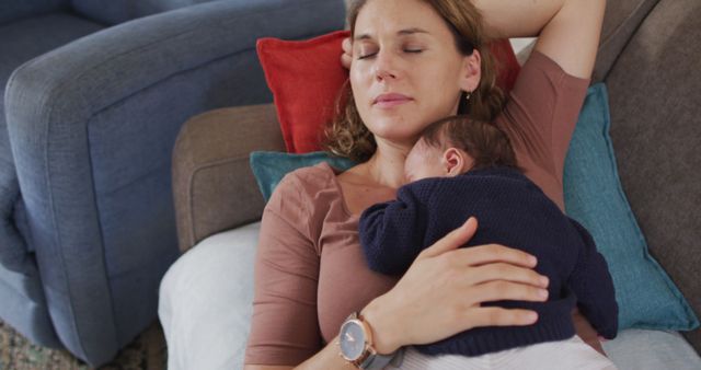 Mother lying on couch with her newborn baby napping on her chest. Perfect for promoting family services, parenting websites, maternity apparel, and ads related to mothers and newborns. Evokes emotions of maternal love and the significance of parent-child bonding moments.