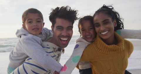 Joyful family enjoying piggyback fun on beach vacation